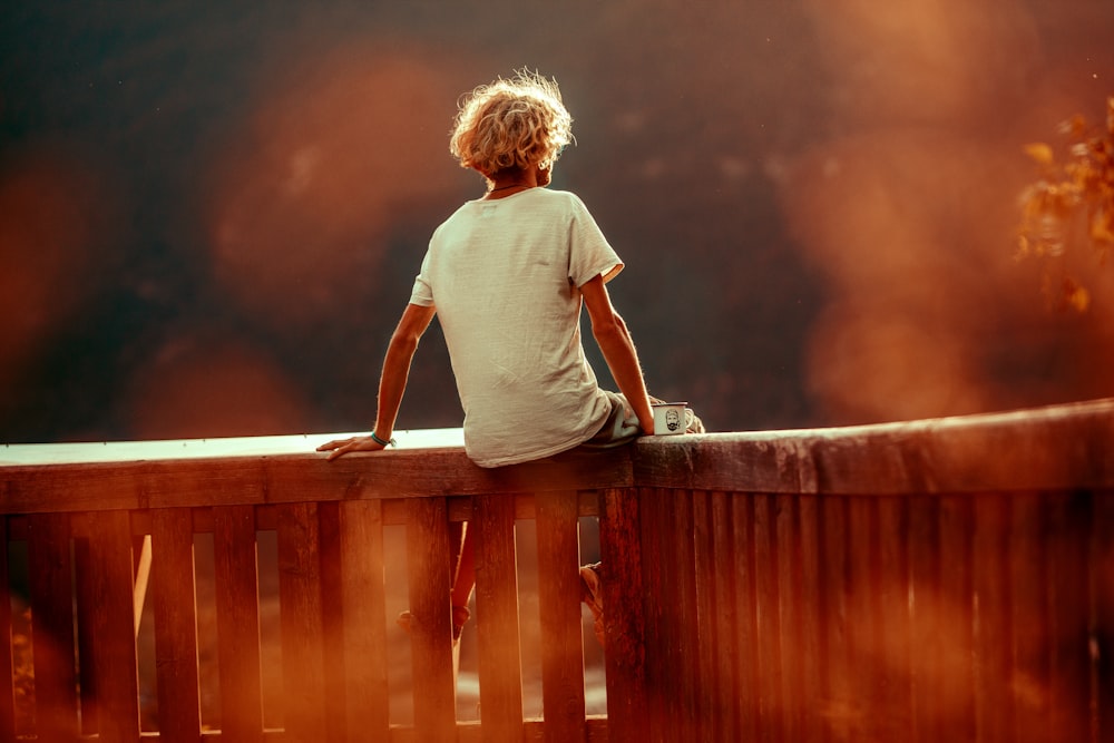 man sitting on edge of railing during daytime