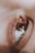A close-up shot of a human eye with detailed focus on the eyelashes and the smooth surrounding skin texture. The eye reflects some light, adding to the depth and detail of the image.