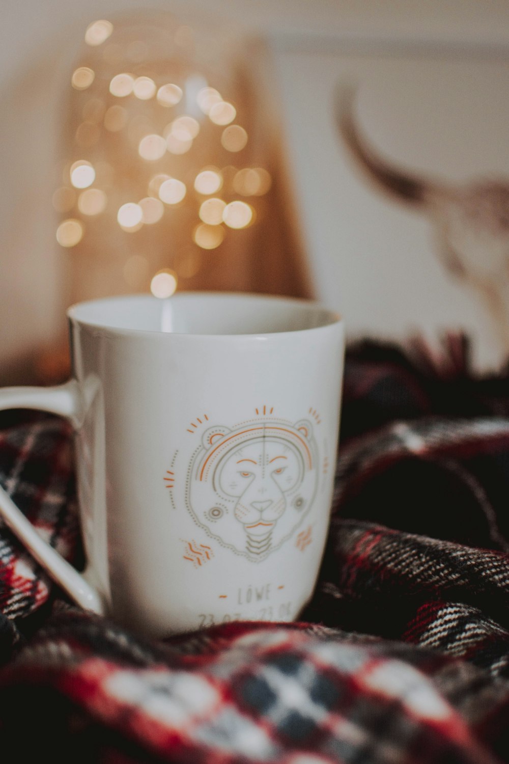 white ceramic mug on black and red textile