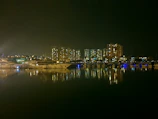 Nighttime cityscape of Dubai Marina glowing behind a moored yacht with ambient lighting.