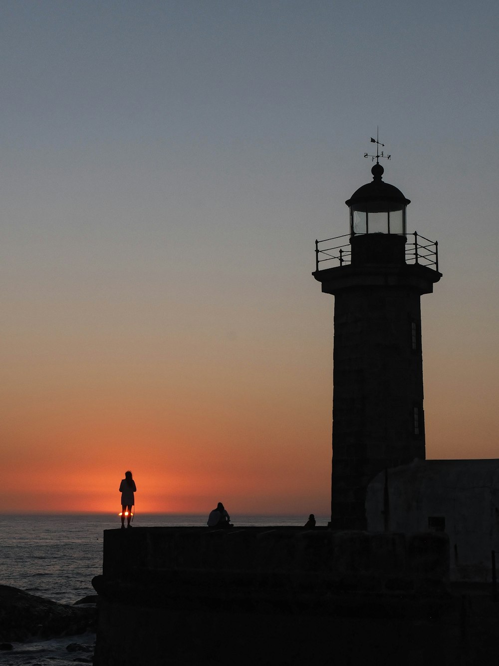 silhouette of person standing near lighthouse
