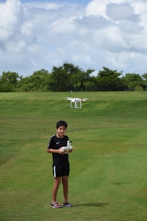 A young participant carefully pilots a drone under the guidance of a mentor in an outdoor STEM workshop.