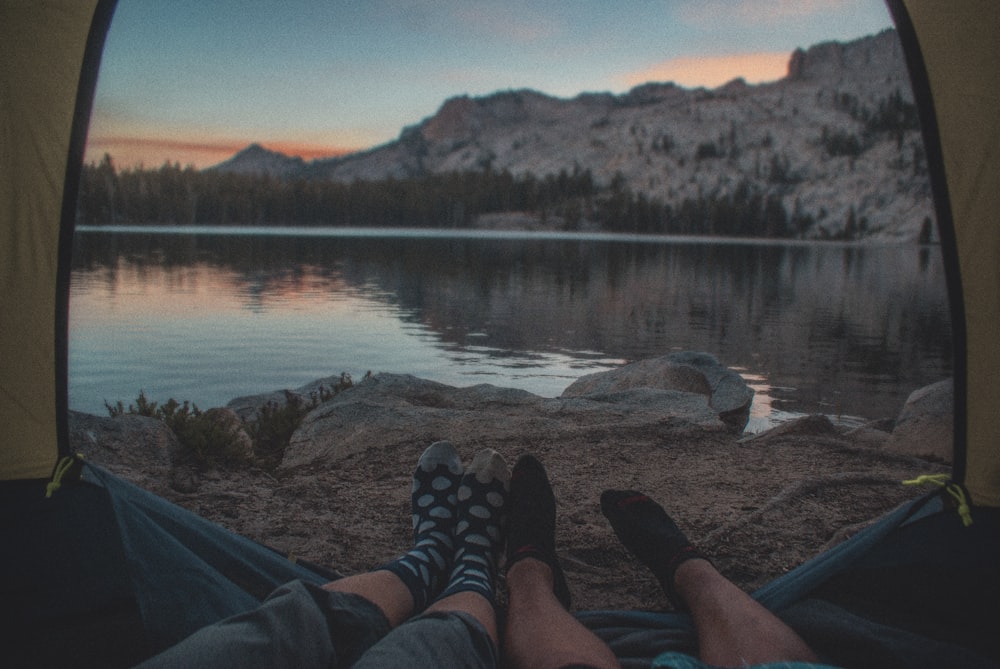 person sitting inside tent beside water