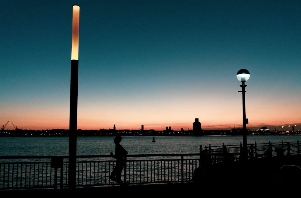 silhouette of man jogging near body of water