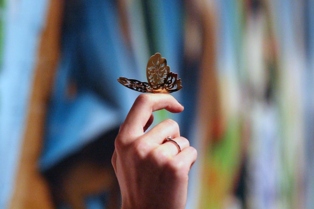 steel butterfly figurine on person's finger