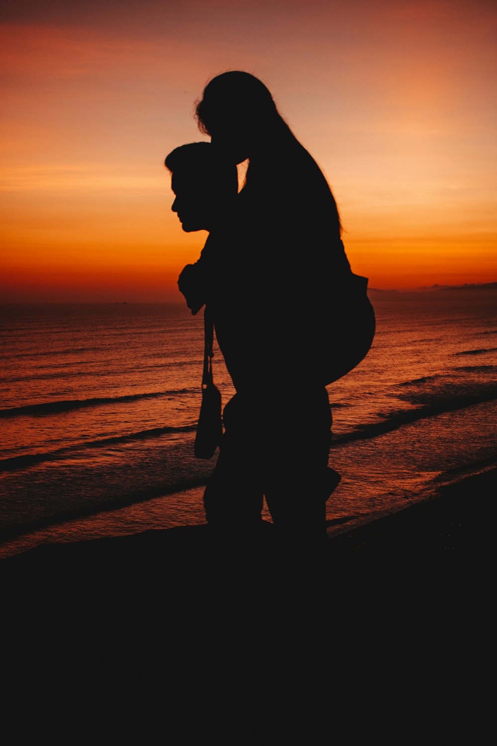 silhouette of two person across sunset