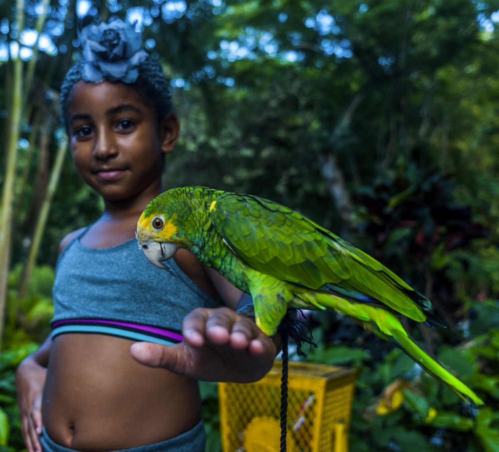 green parrot perched on girl's arm