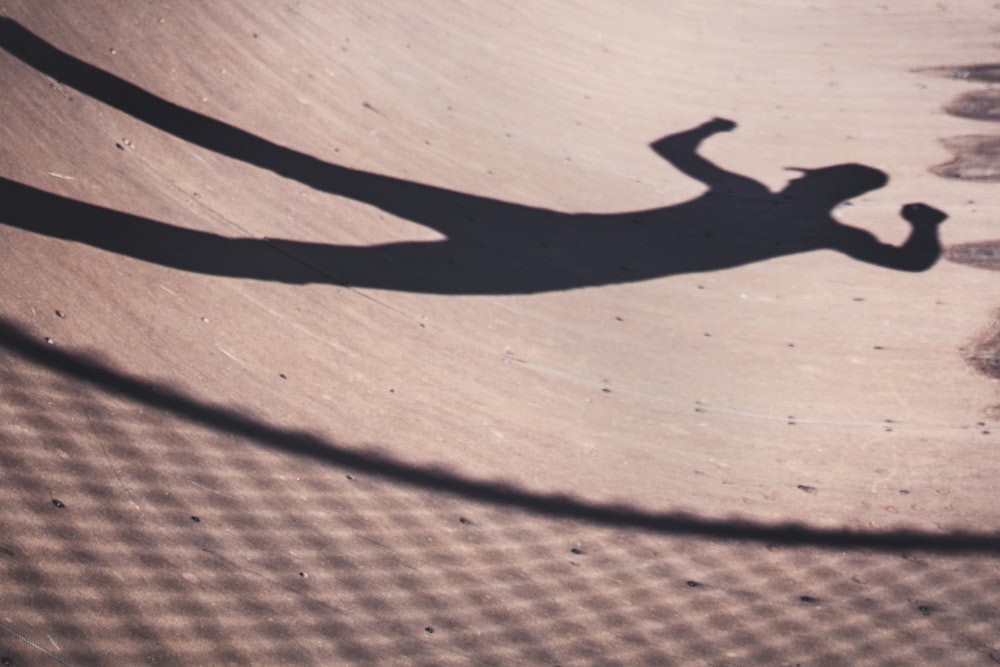 shadow of man near fence on sand