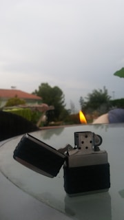 Windproof lighter with flame against a blurred outdoor background showcasing durability