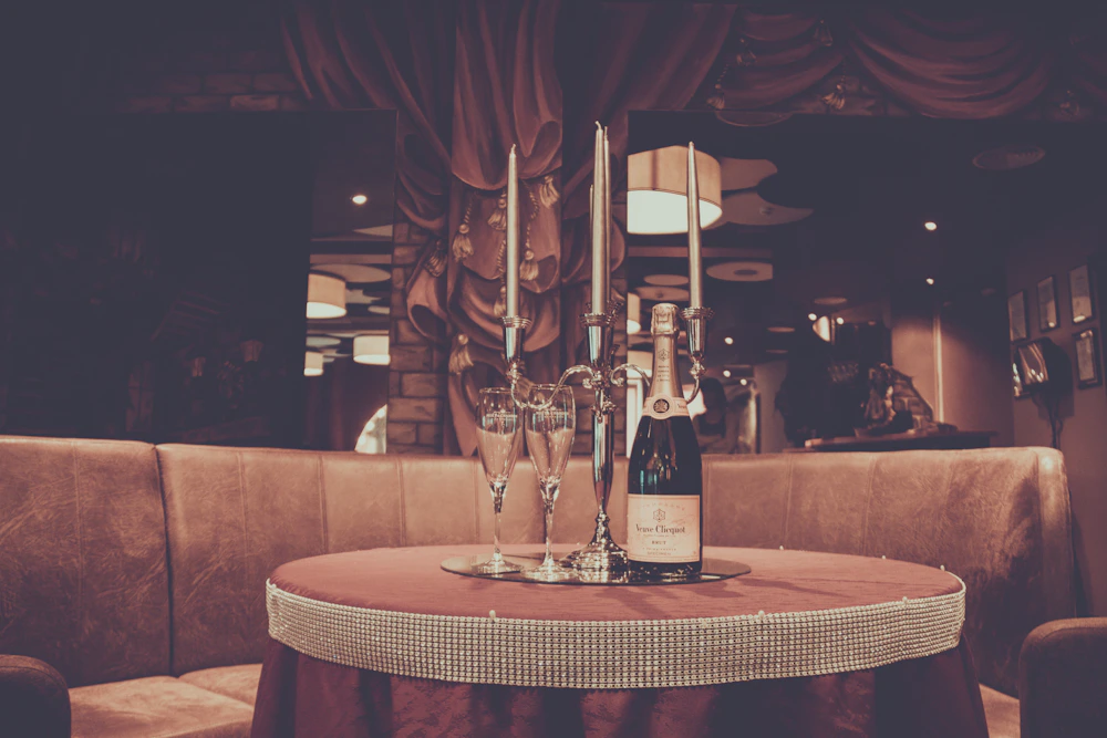 A wine bottle, glass and candle on a formal dining table