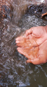 Close-up of hands purifying water with portable filtration equipment outdoors.