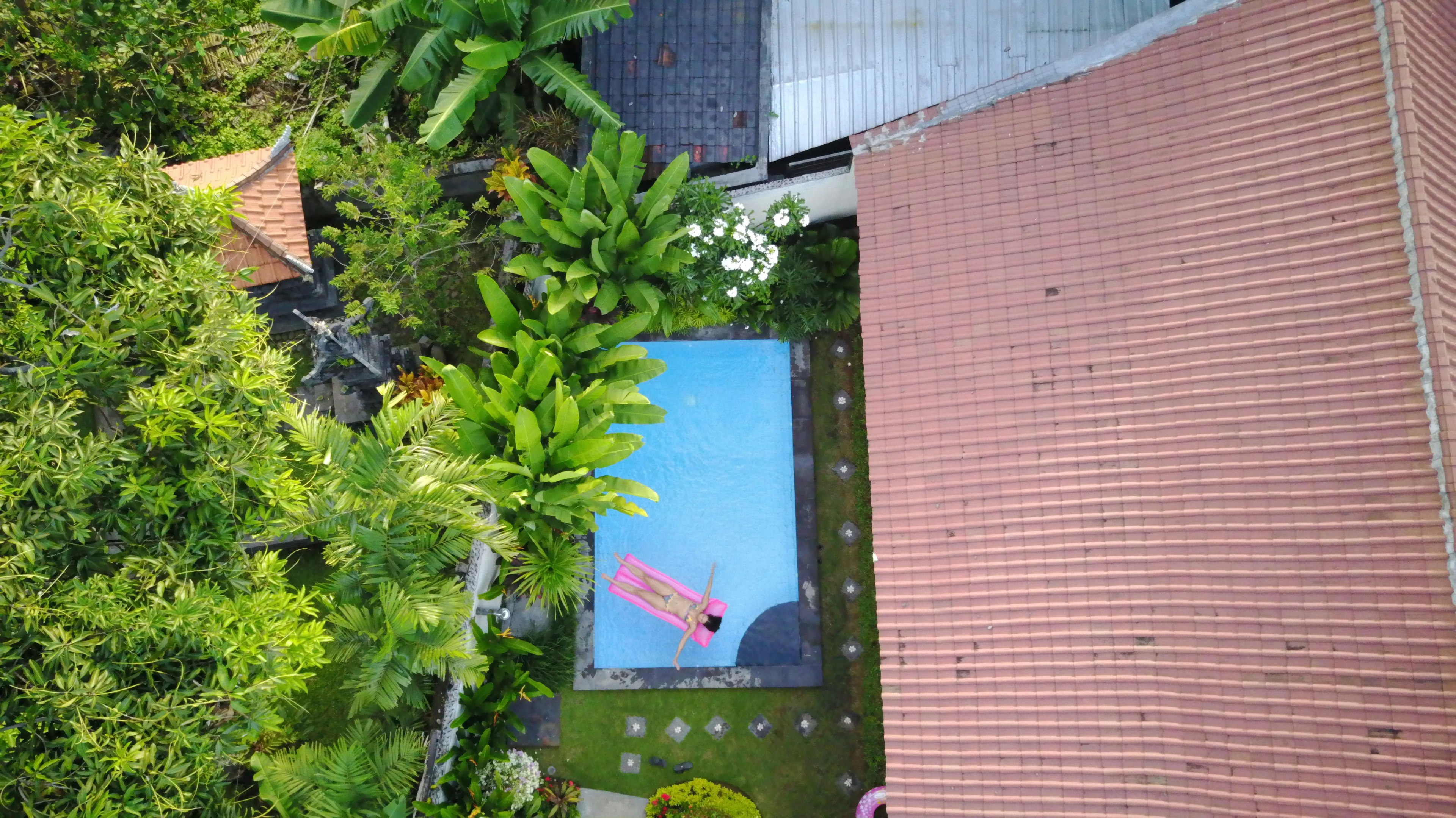 top view of woman lying on pink swimming bed at at swimming pool