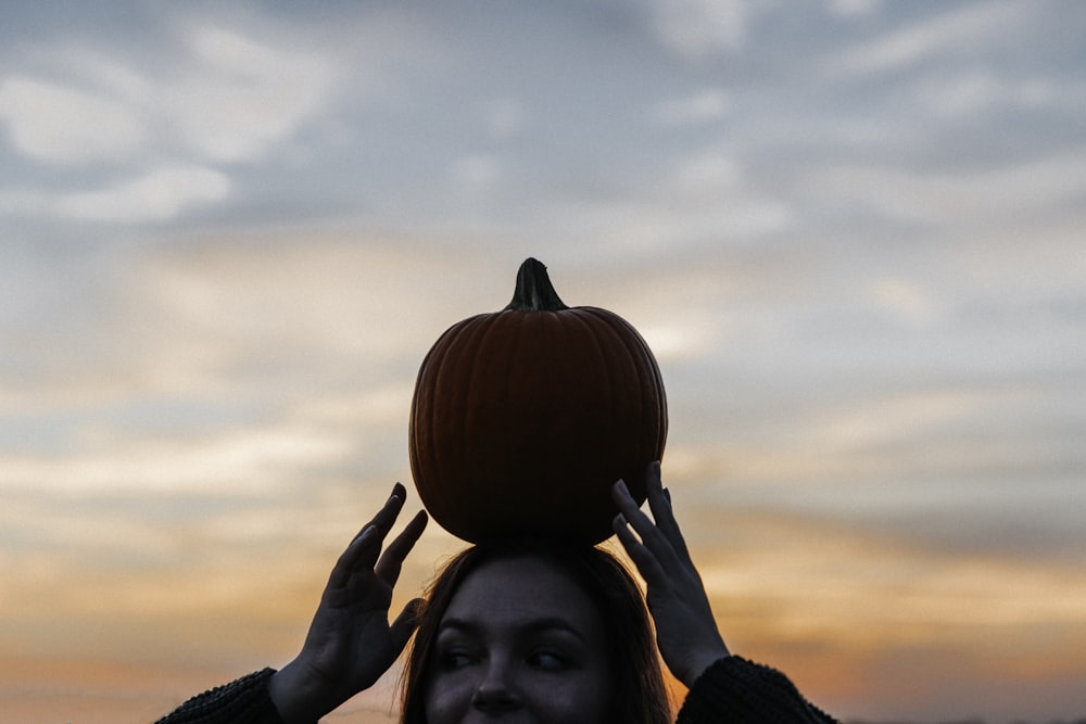 woman carrying pumpkin on head