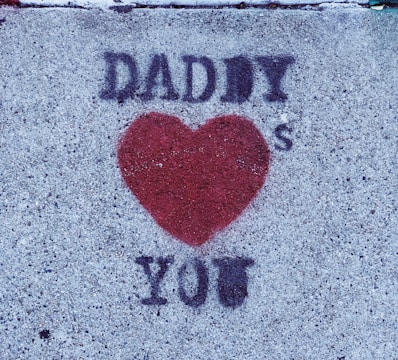Graffiti on a concrete surface with the words 'Daddy ❤️ You' in black around a red heart shape.