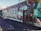 A wall featuring vibrant graffiti art in a variety of colors and abstract designs. The artwork includes intricate patterns and lettering, with a mix of teal, green, orange, and black hues. The area is outdoors and the scene includes a metal gate with engraved details.