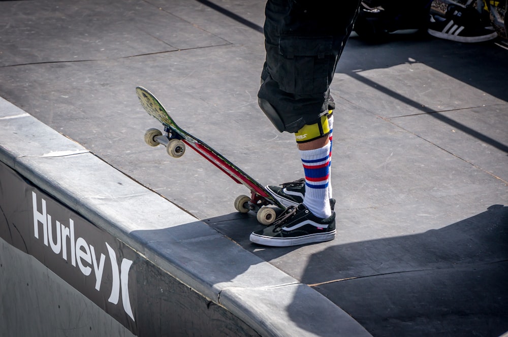 person stepping skateboard on tip beside Hurley signage