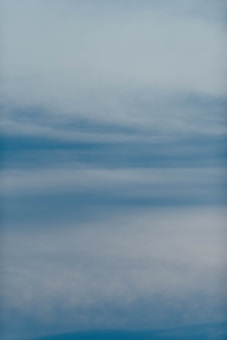 Soft layers of blue and gray hues blend to create a serene and tranquil sky-like appearance. The gradient suggests light clouds or misty weather, evoking a sense of calmness and relaxation.