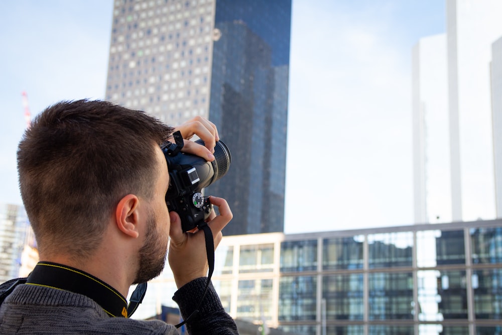 man standing and taking photo of high-rise buildings