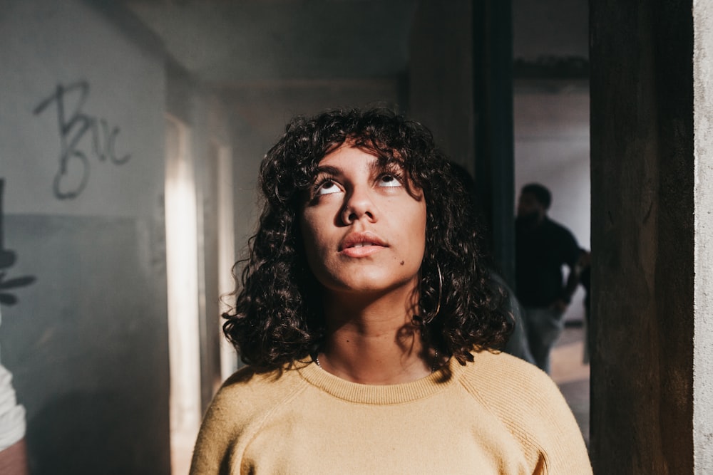 mulher vestindo camisa amarela em pé dentro do quarto