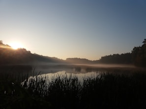 A serene sunrise over a quiet lake with soft mist, symbolizing new beginnings in prayer.