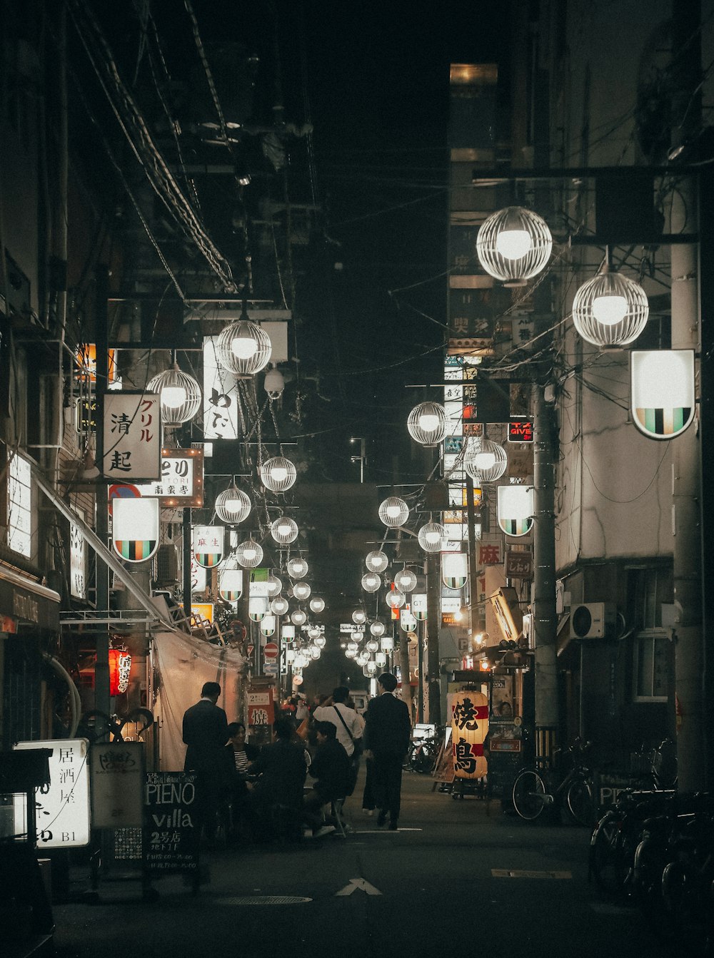 people walking on street betweein lamps
