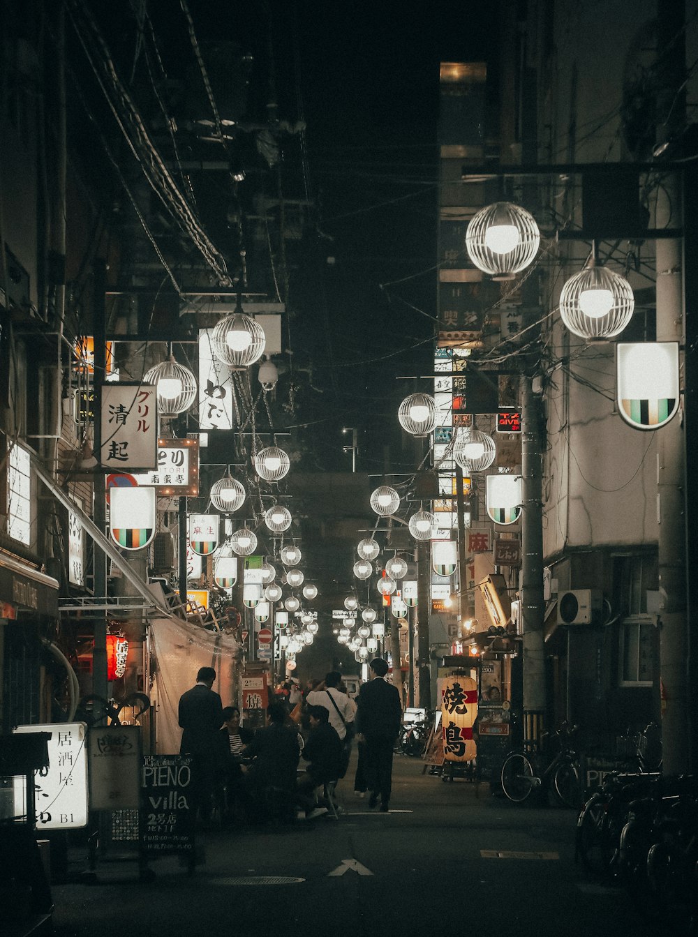 personnes marchant dans la rue entre les lampes