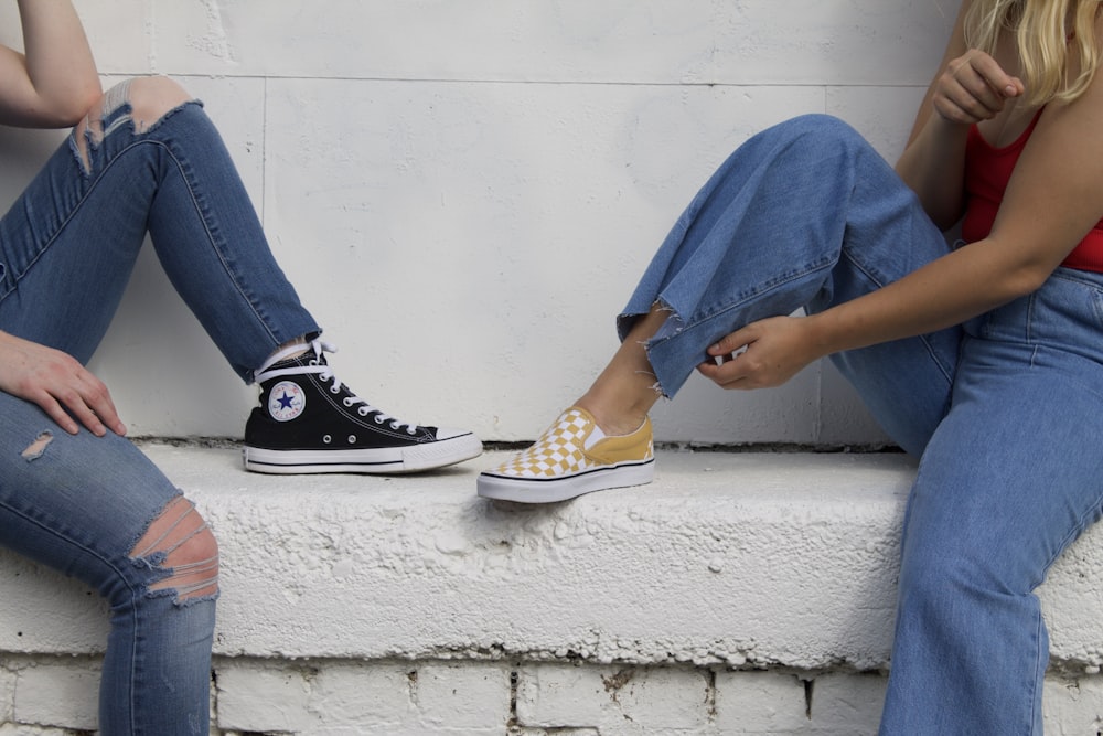 two women sitting on gray concrete bench