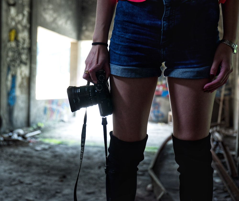 person in blue denim shorts holding camera