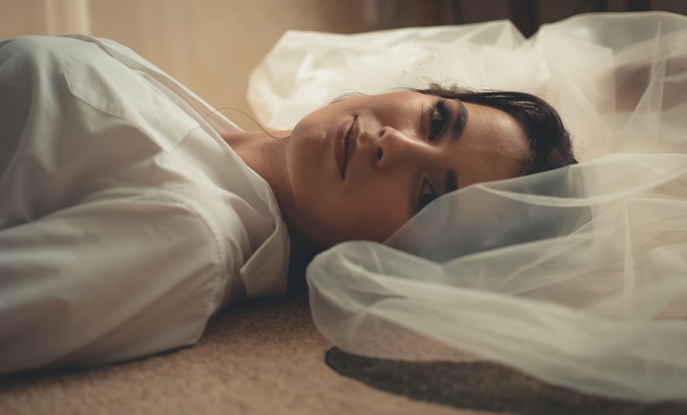 woman lying on the floor wearing white veil