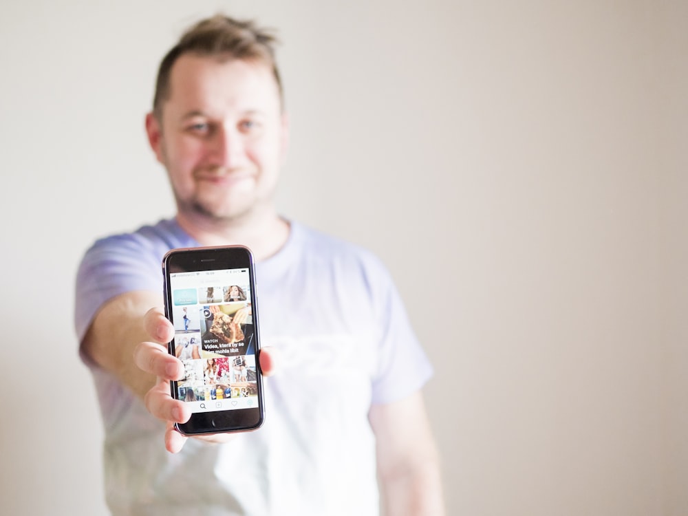 man wearing grey shirt holding smartphone