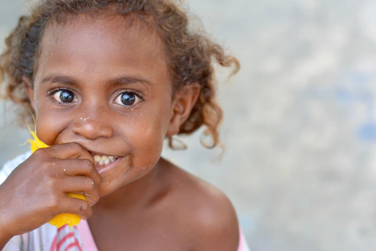 A smiling child holding a colorful plate filled with fresh fruits and vegetables.