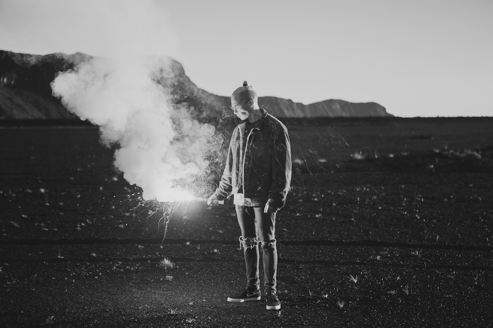 grayscale photo of man holding sparklers