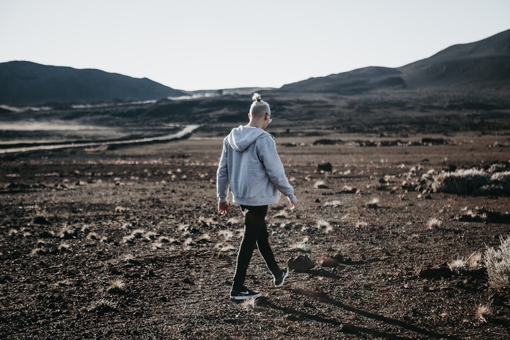 man in hoodie walking on open field