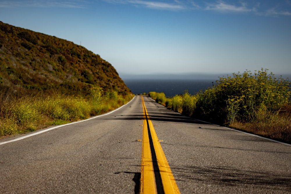 carretera asfaltada gris cerca de la vista de campo verde bajo cielos azules