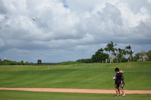 Kids flying drones in an outdoor field during a drone soccer match.