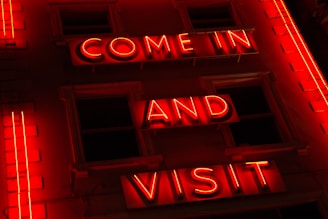 Bright red and white illuminated sign glowing on a storefront at night.