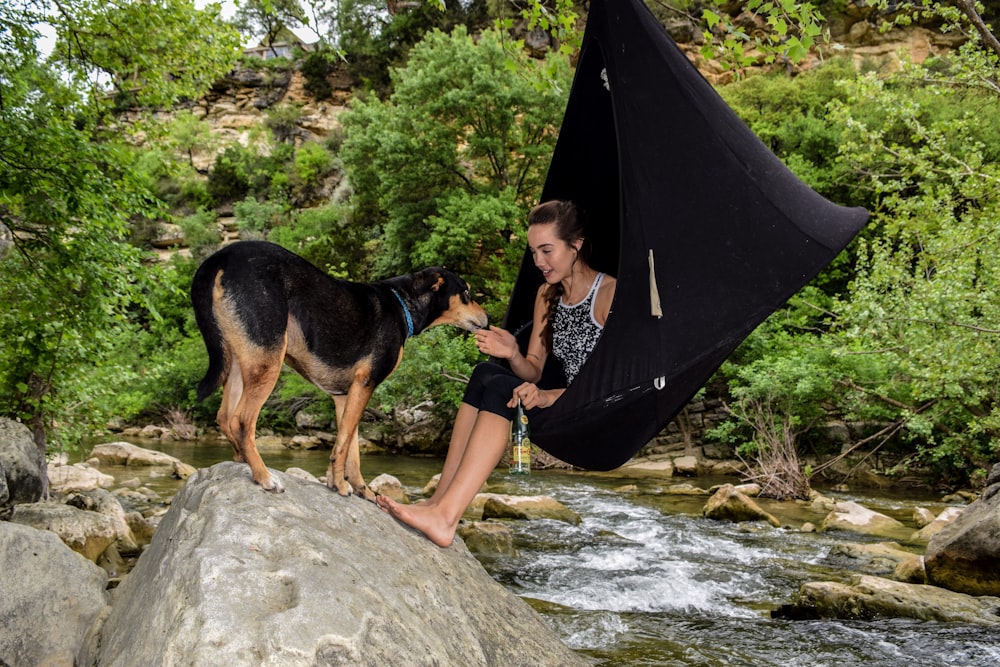 woman sitting on hammock in front of dog