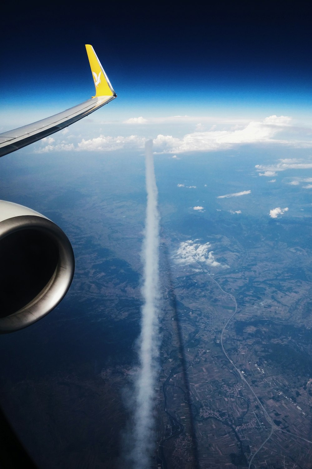 contrail streaming below flying aircraft