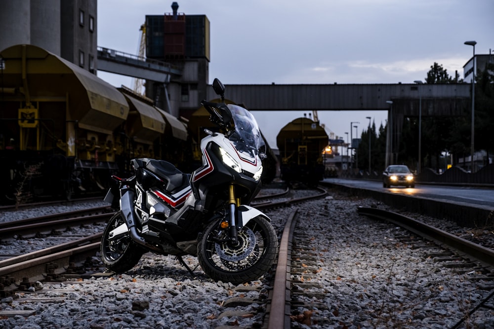 black and white sports motorcycle in the middle of train railway