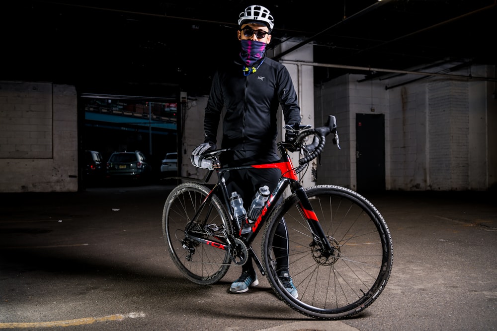 man wearing pants standing beside road bike