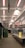 An indoor market with metal stalls and bright overhead lights. The walls are adorned with large Union Jack flags, and there are warning signs placed around indicating potential hazards. The market appears empty and quiet, with no people present.