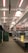 An indoor market with metal stalls and bright overhead lights. The walls are adorned with large Union Jack flags, and there are warning signs placed around indicating potential hazards. The market appears empty and quiet, with no people present.