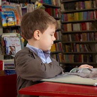 Young boy sitting in a school library reading a book