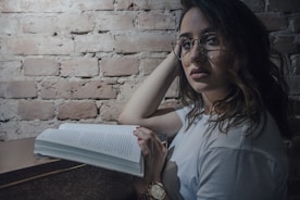 Elegant studio shot of a mature author with glasses, seated with a book.