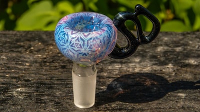 Handcrafted glass smoking piece with vibrant colors glowing under warm lighting.