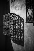 Detail image of a roster beton with intricate floral design casting shadows on a white wall.