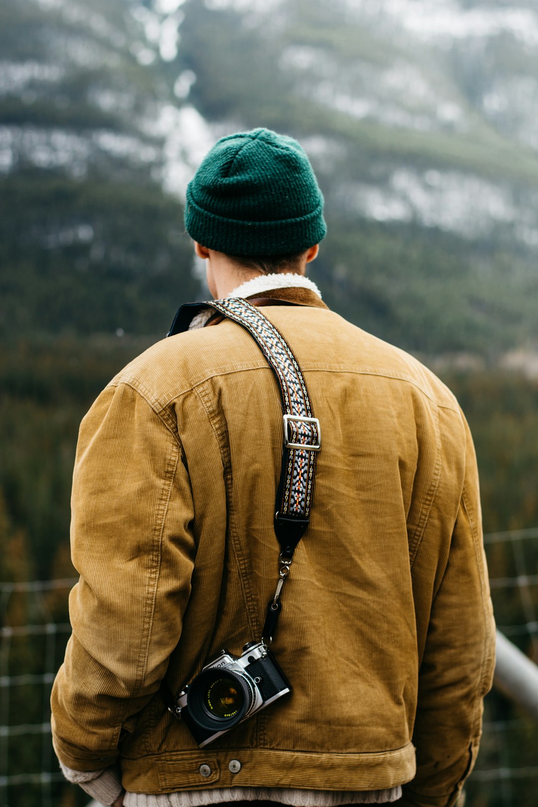 man in brown coat with DSLR camera