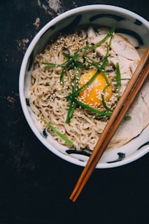 A steaming bowl of golden ginger chicken ramen topped with fresh scallions and a soft-boiled egg.