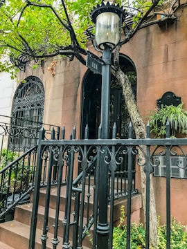 Historic NYC townhouse with a wrought iron fence and lush greenery.
