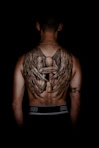 person with kneeling angel back tattoo